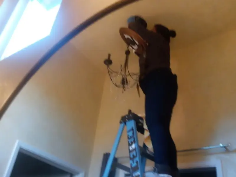 Electrician installing a chandelier in a Buckhorn residence